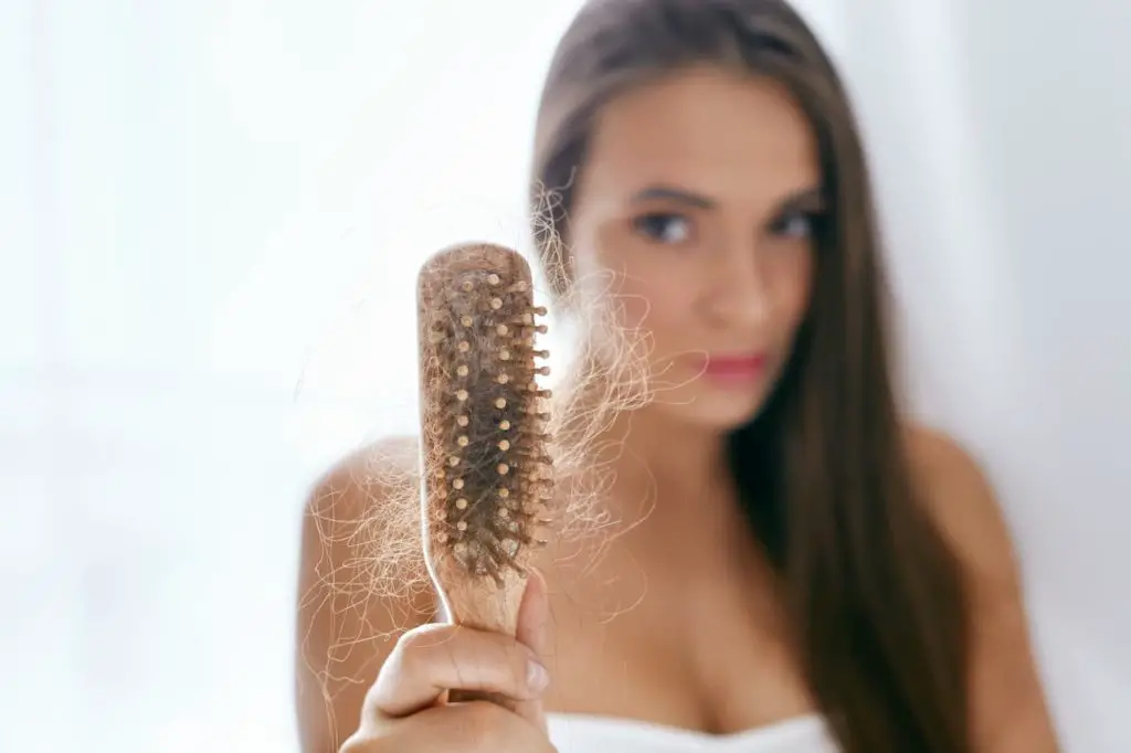 Woman holding a brush with lots of hair in it - What Are Some Carnivore Diet Hair Loss Causes