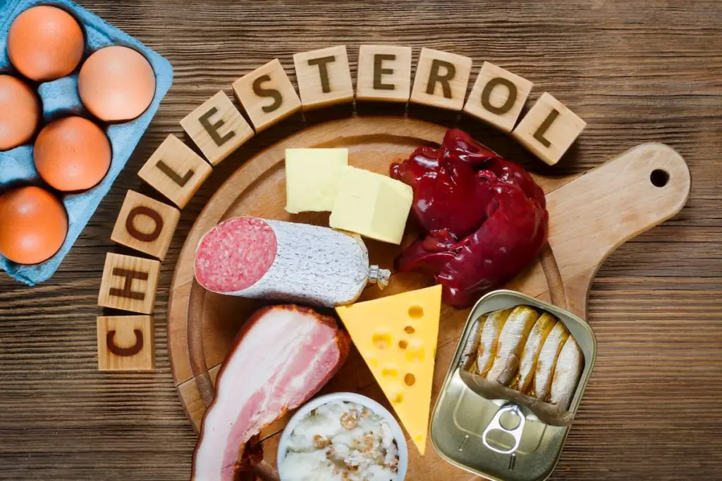 Cholesterol spelled out with blocks, meat on a table - How Does the Carnivore Diet Affect Cholesterol