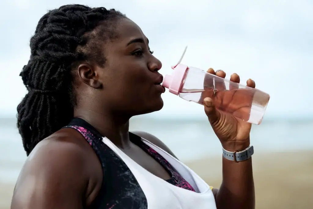 Lady drinking water from a sports water bottle - How Much Water Should You Drink on Carnivore Diet