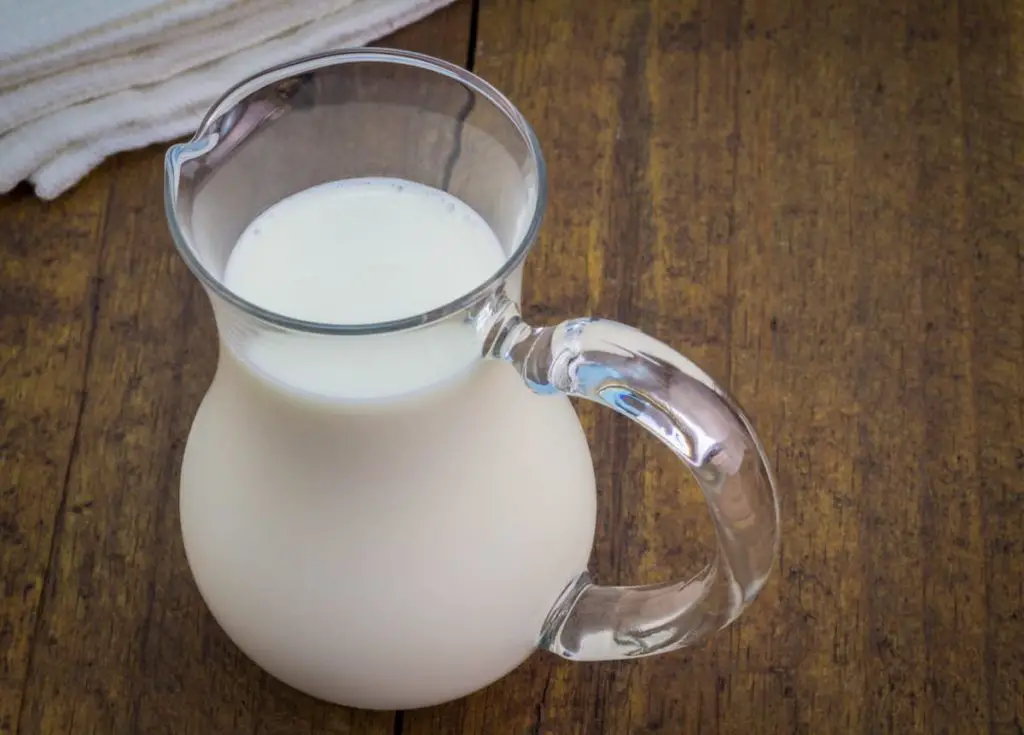 Natural whole milk in glass jug on rustic wooden table - Can You Drink Milk on the Carnivore Diet