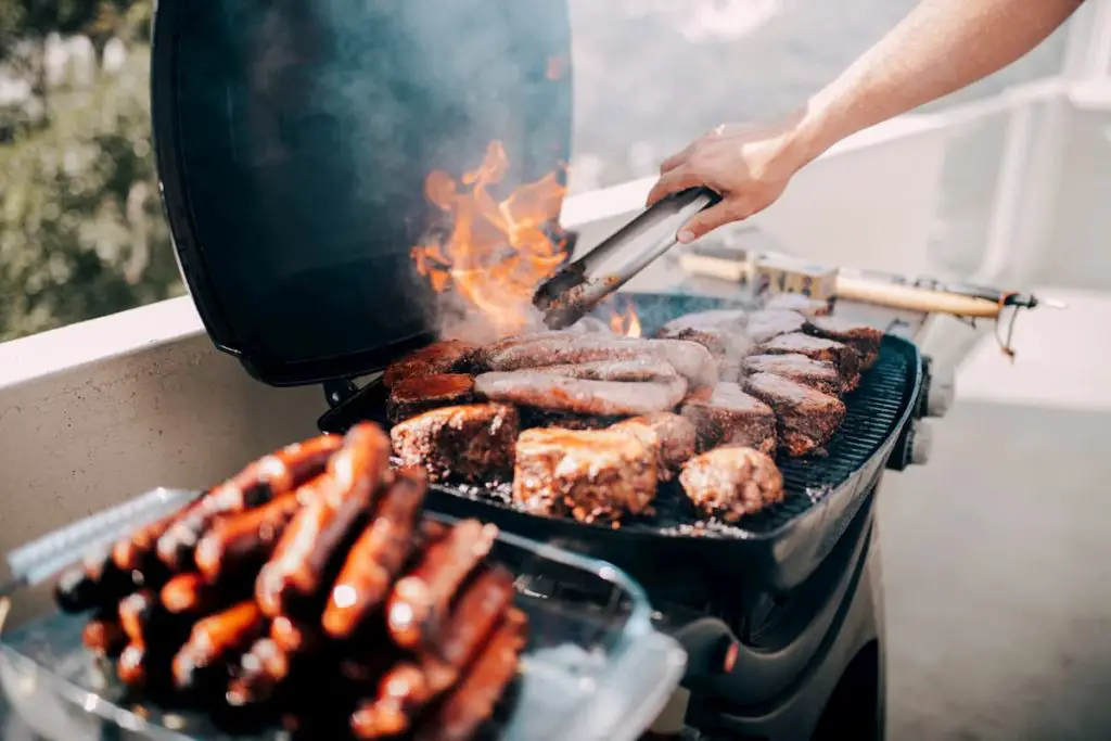 Close-up of man grilling lots of meat on barbecue with flames - Carnivore Diet Eating Plan